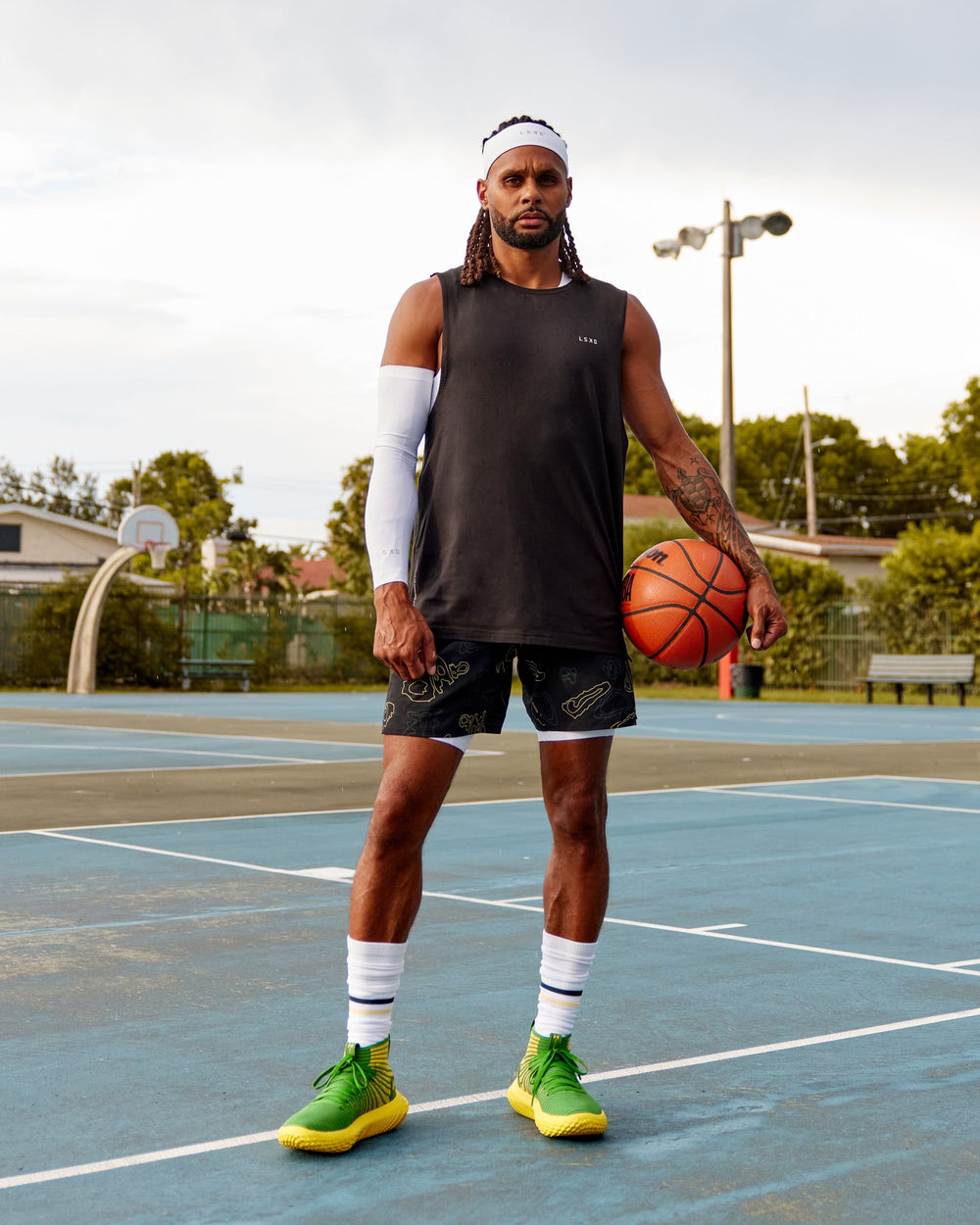 Man wearing Patty Mills Challenger 6" Performance Shorts - Black-Vital Green