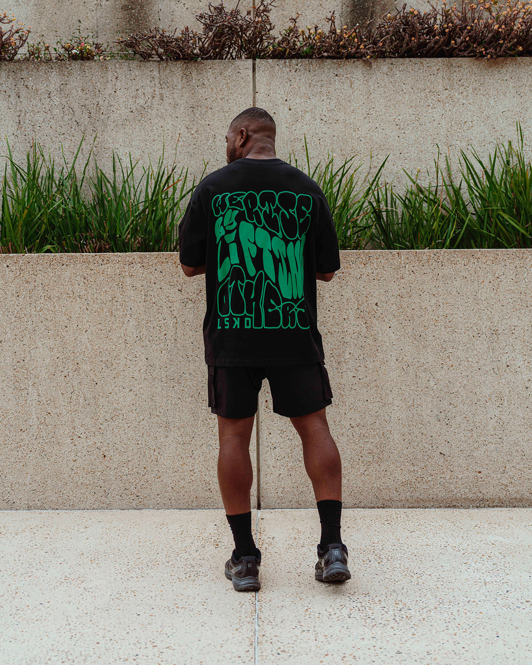 Man wearing Unisex We Rise Heavyweight Tee Oversize - Black-Impact Green