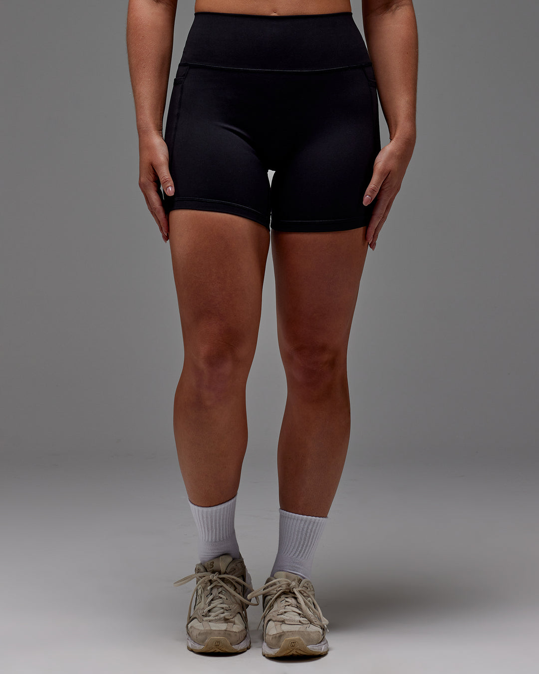 Woman wearing Fusion Mid Short Tight With Pockets in Black | Model:Meg | Size:M