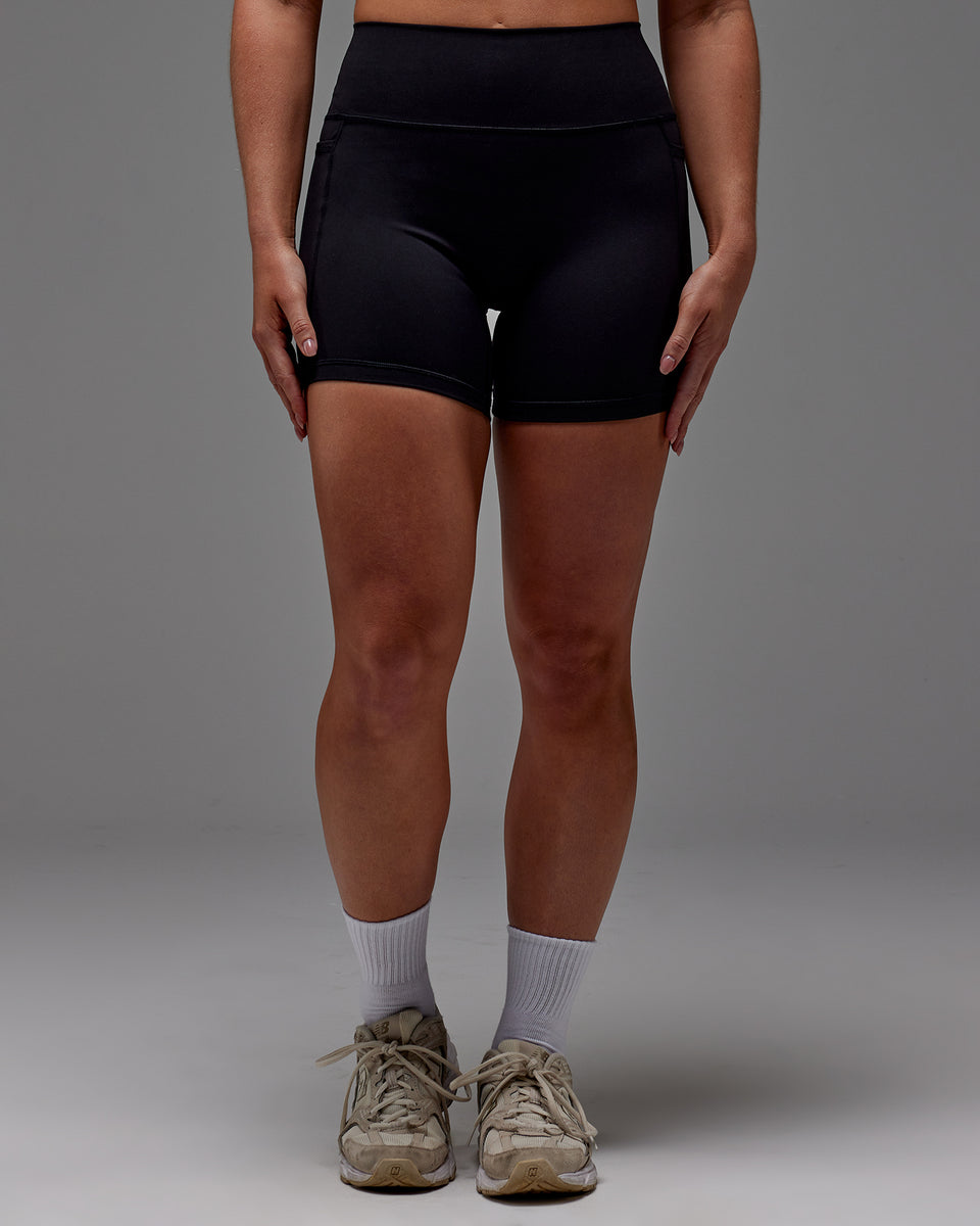 Woman wearing Fusion Mid Short Tight With Pockets in Black | Model:Meg | Size:M