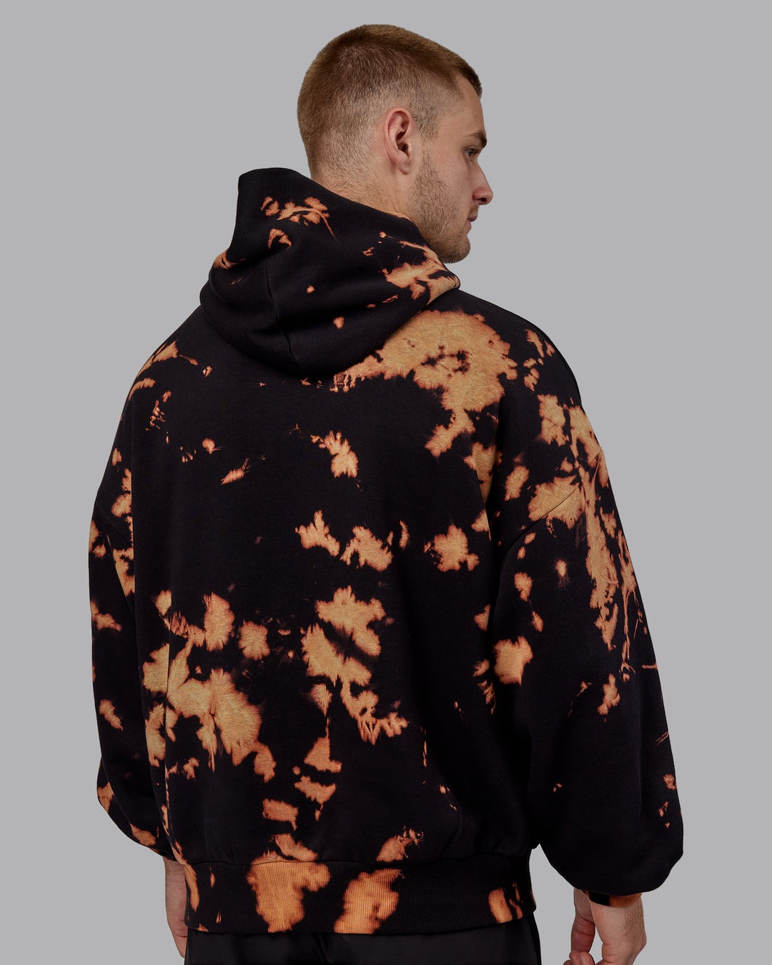 Man wearing Unisex 1% Better Hoodie Oversize - Black-Bleach-Tie Dye