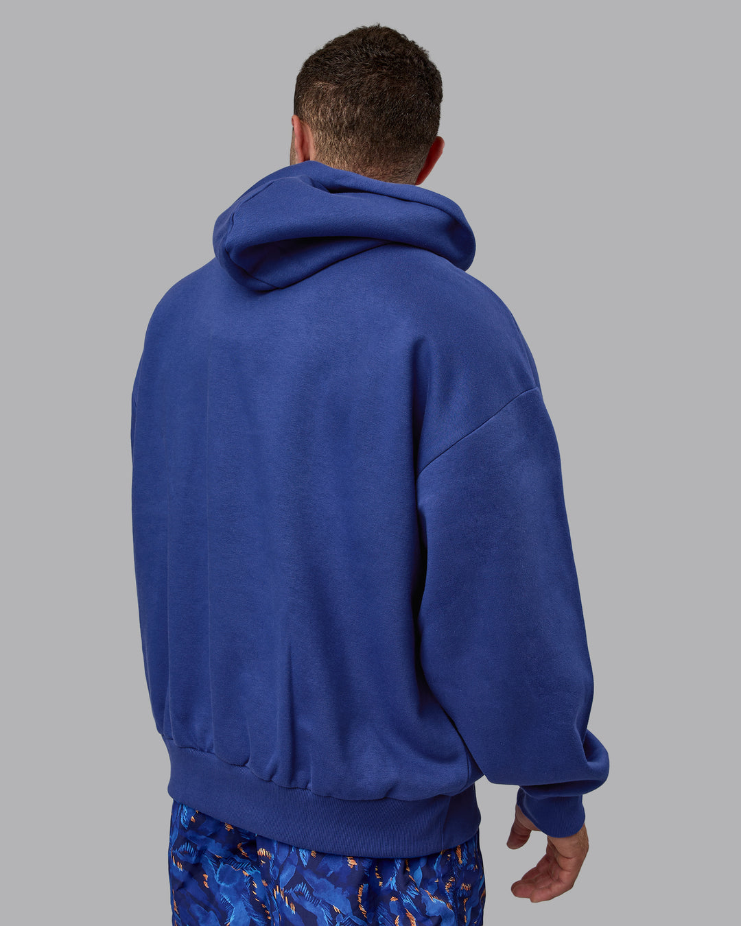 Man wearing Unisex Motion Hoodie Oversize - Galactic Cobalt-Vibrant Orange