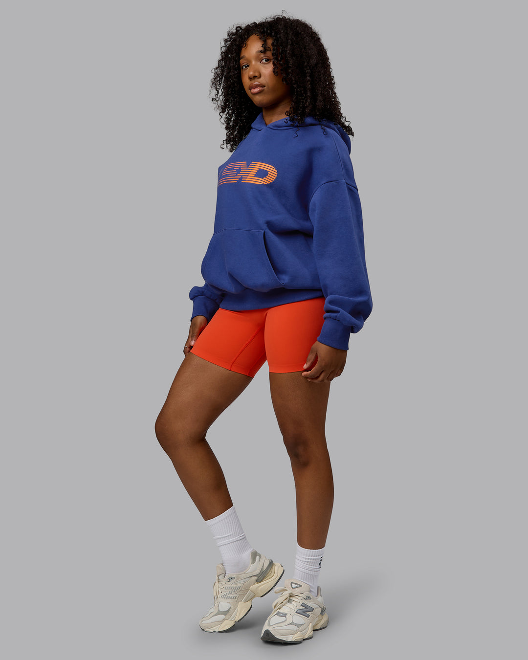 Woman wearing Unisex Motion Hoodie Oversize - Galactic Cobalt-Vibrant Orange