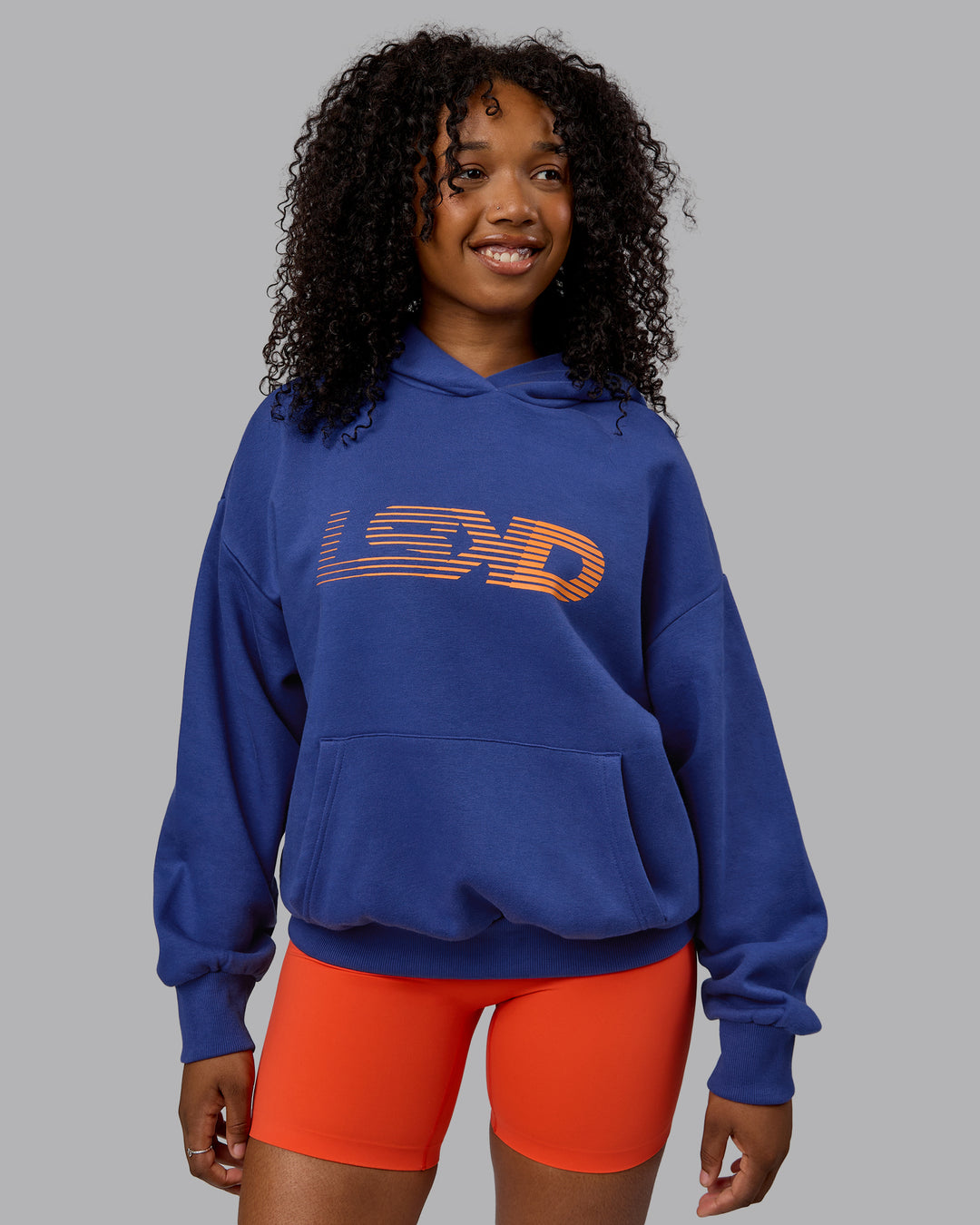 Woman wearing Unisex Motion Hoodie Oversize - Galactic Cobalt-Vibrant Orange