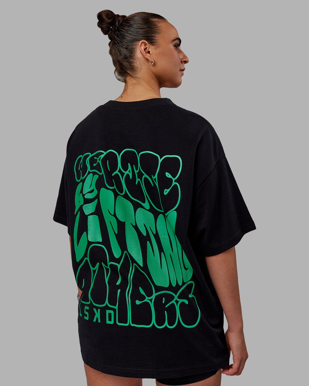 Woman wearing Unisex We Rise Heavyweight Tee Oversize - Black-Impact Green