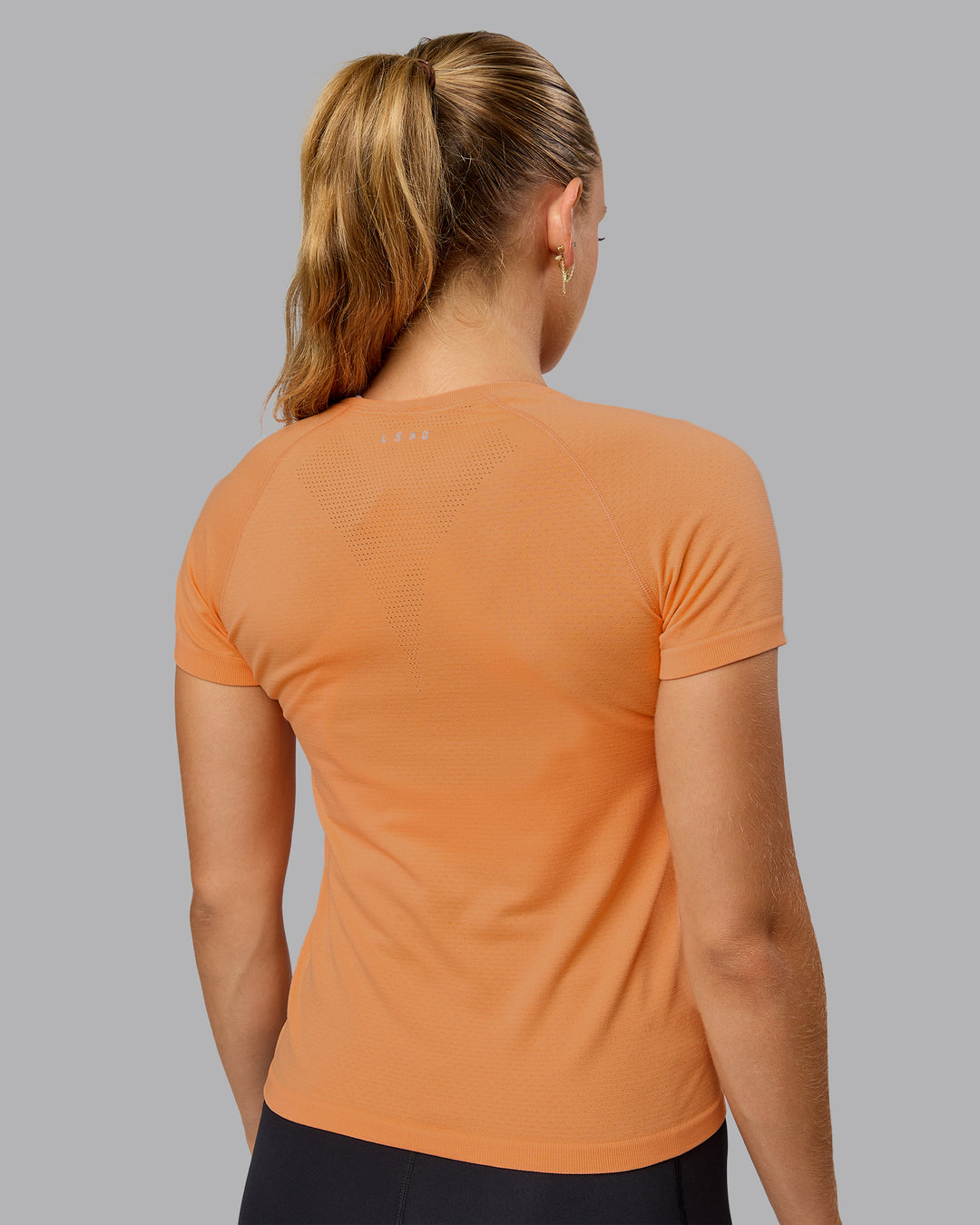 Woman wearing AeroFLX+ Seamless Tee - Cantaloupe