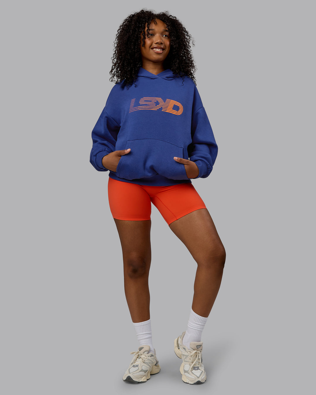 Woman wearing Unisex Motion Hoodie Oversize - Galactic Cobalt-Vibrant Orange