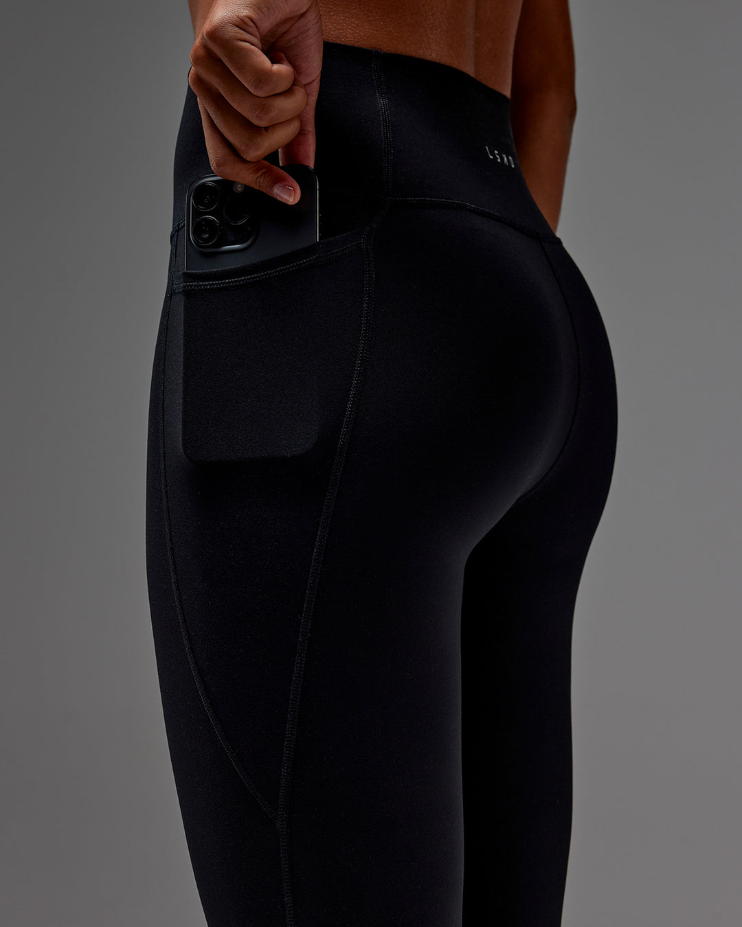 Woman wearing Fusion 3/4 Length Tight with Pockets in Black | Model:Txai | Size:XS